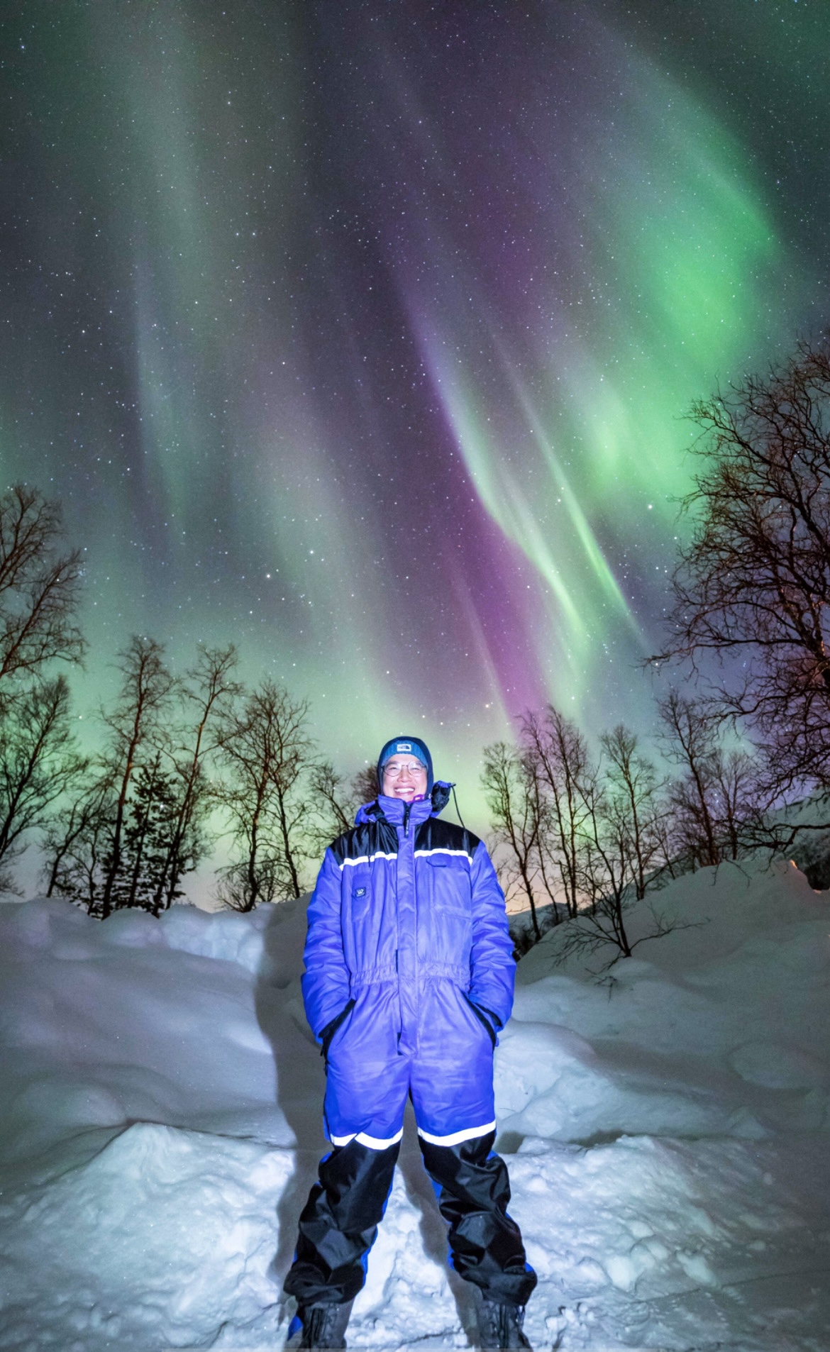 Remi Levinson, Scheller Full-time MBA ’24, stands in a snow suit beneath a night sky ablaze with the Northern Lights. 