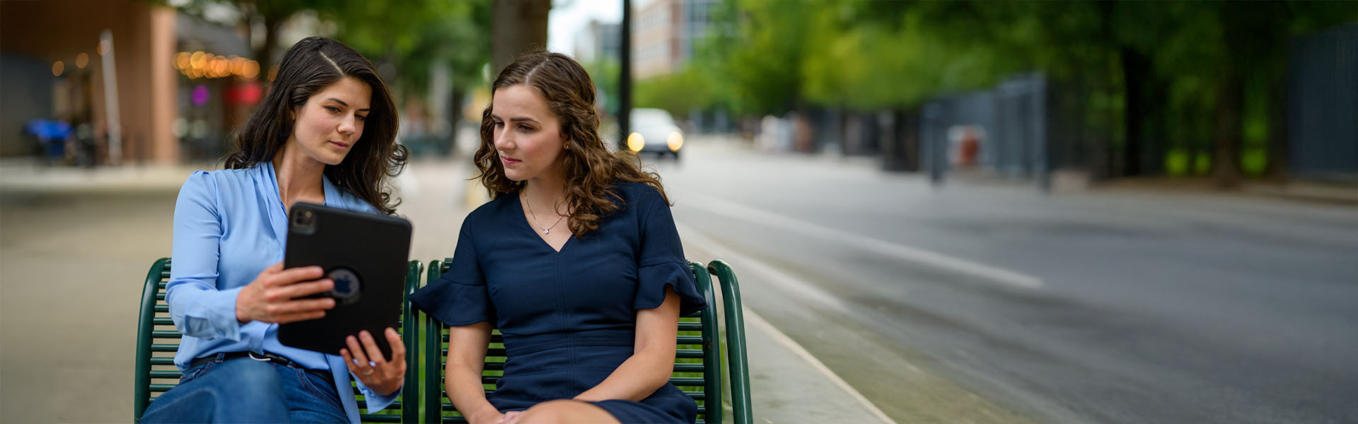 Two women sitting on bench outside of Scheller