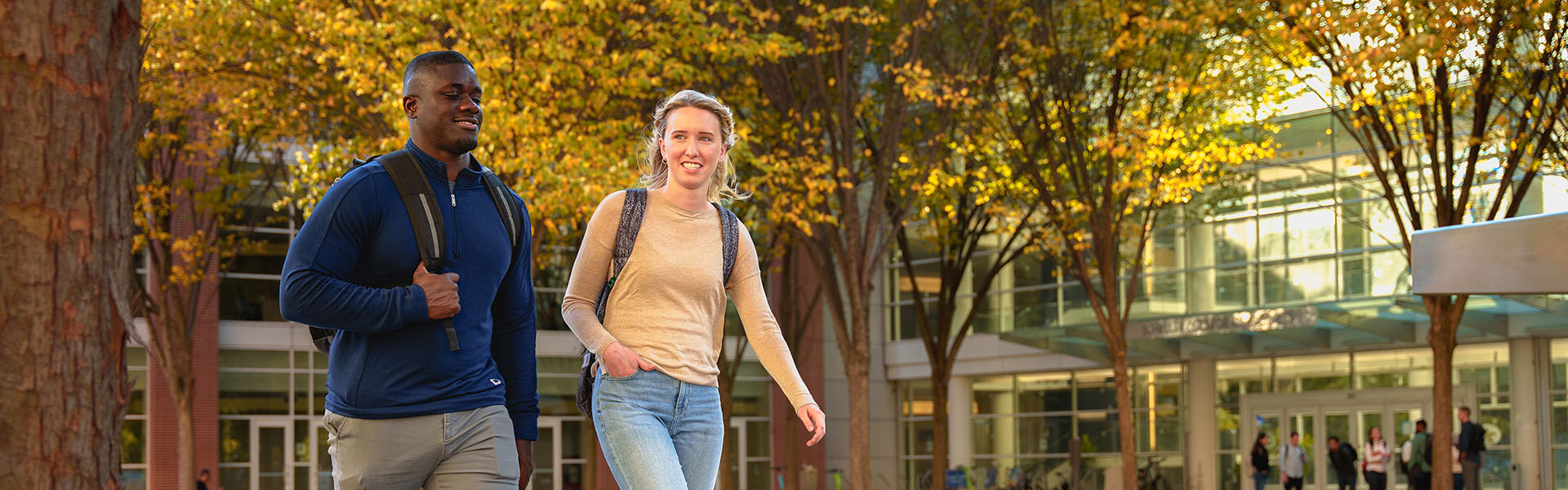 Two Scheller students walking on sidewalk in the fall