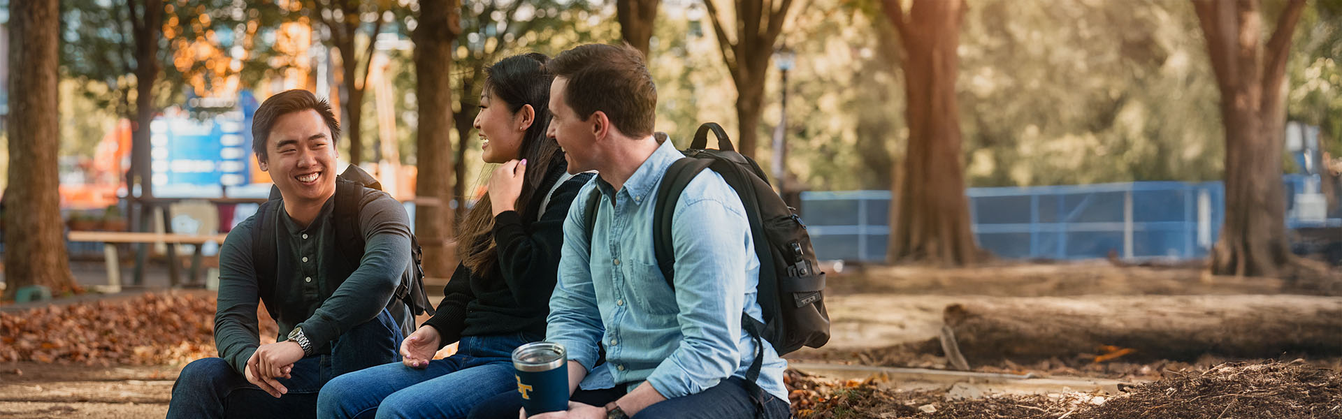 Three casual Scheller students sitting, chatting, and smiling, outside