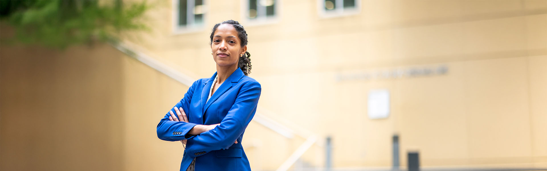 Female MBA dual degree student in blue dress arms crossed in Scheller courtyard