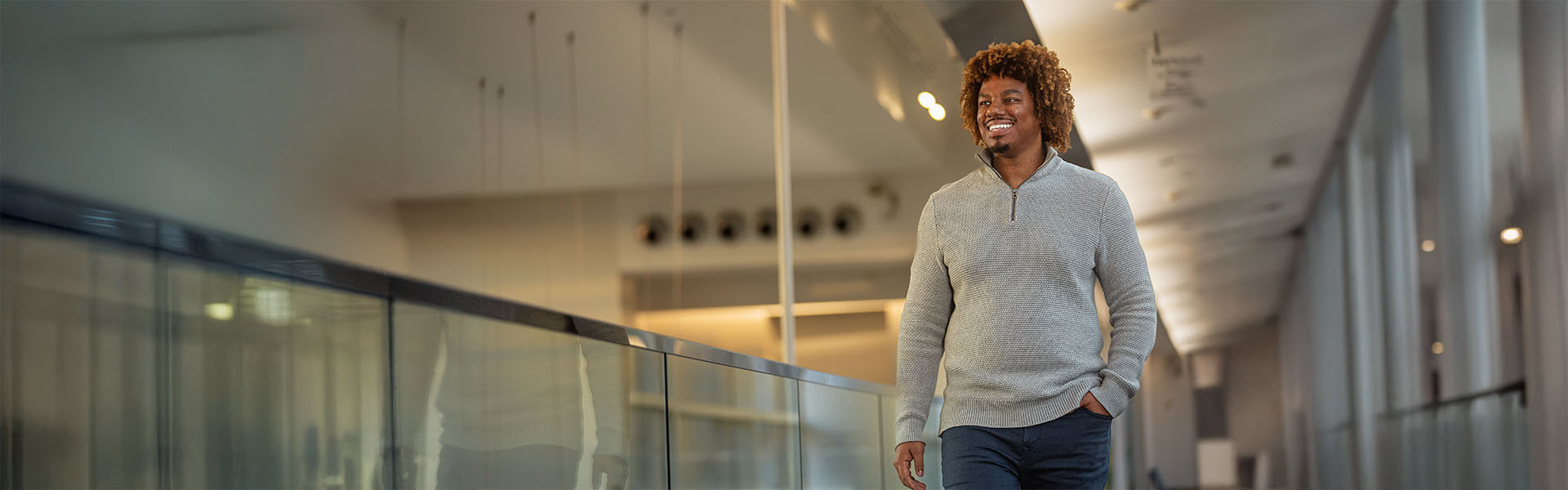 Engineering student in casual half zip sweater walking inside Scheller building