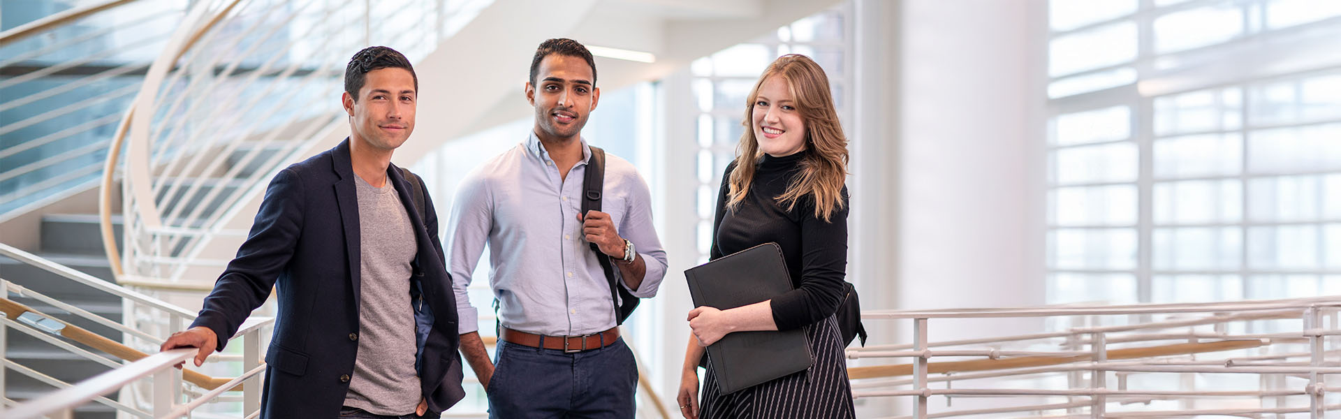 Three Scheller students posing in front of staircase