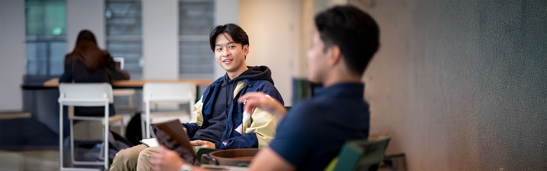 Two undergraduate business students, wearing Georgia Tech jackets, sitting and chatting with each other