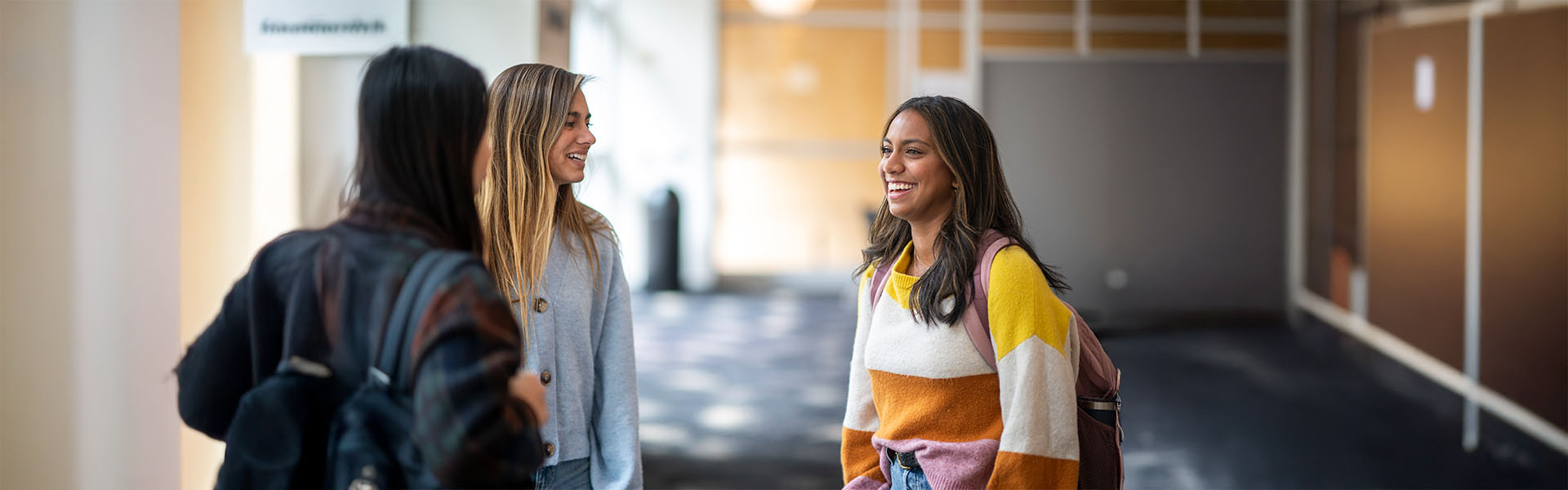 Three female undergraduate students chat in front of finance office