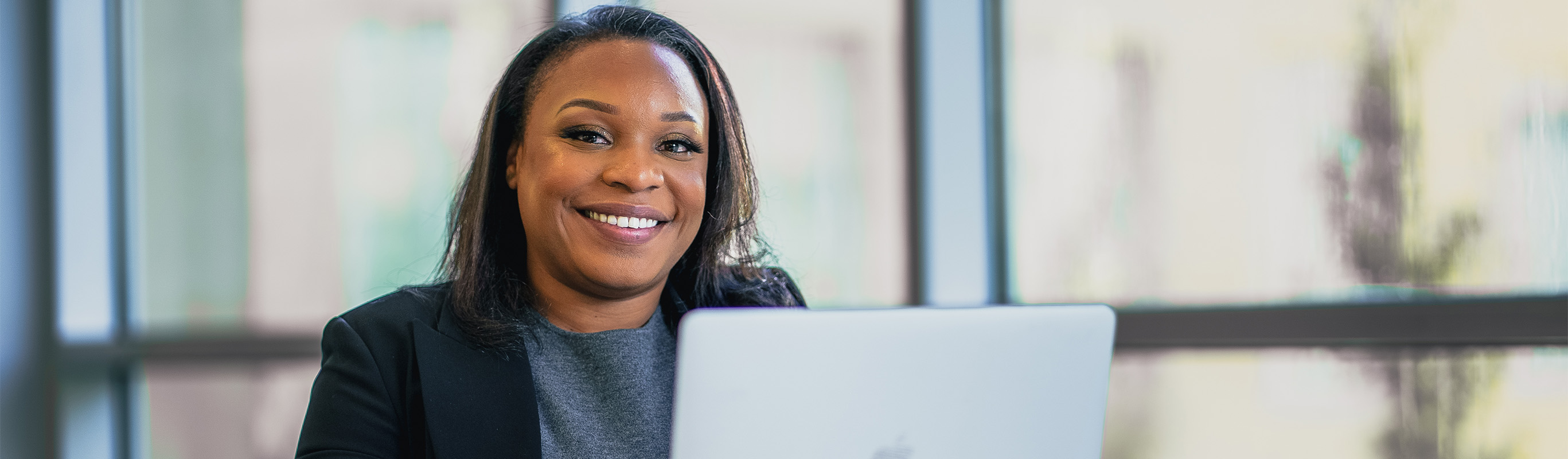 A female student sits smiling over her laptop