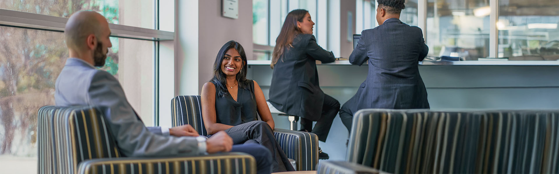 Four Scheller students, two seated, two on high-top table, chatting and interacting