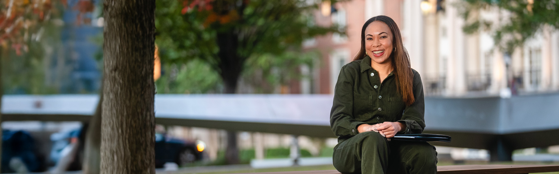 Female MBA student, sitting outside Scheller building, smiling at camera, wearing a green one-piece outfit