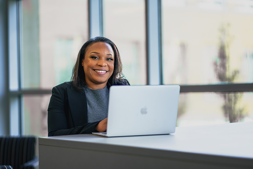 A female student smiles while working from a laptop