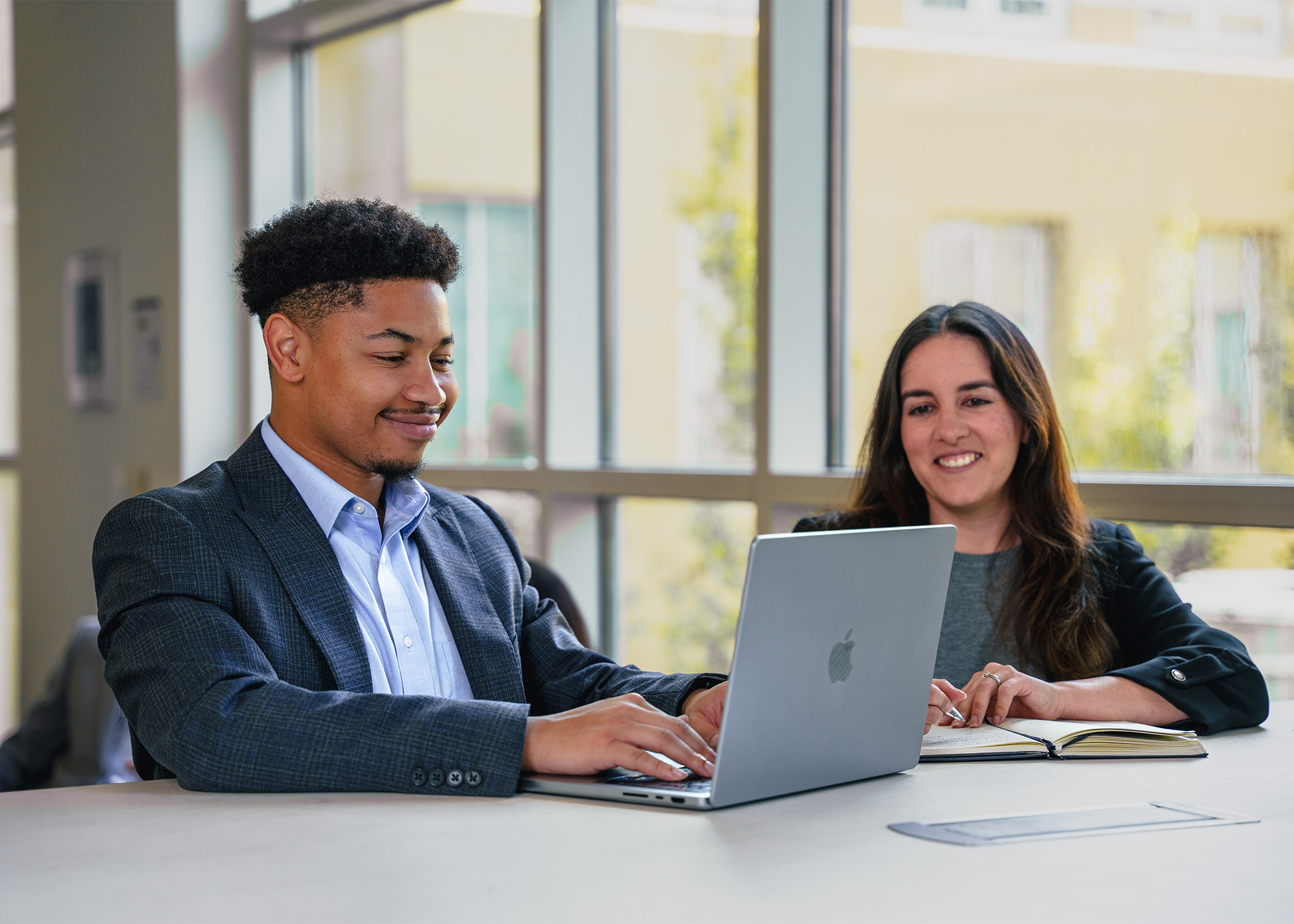 Two students, one male and one female, sit and work in front of a laptop