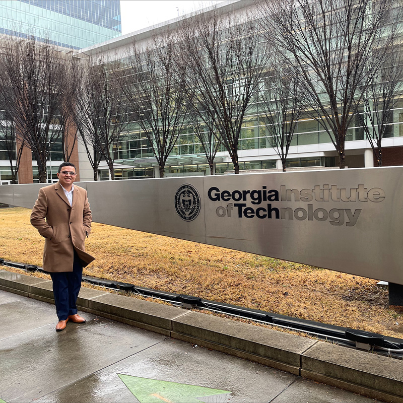 Ciro Baires, Evening MBA ’23, stands outside the Scheller College of Business intersection on a rainy day