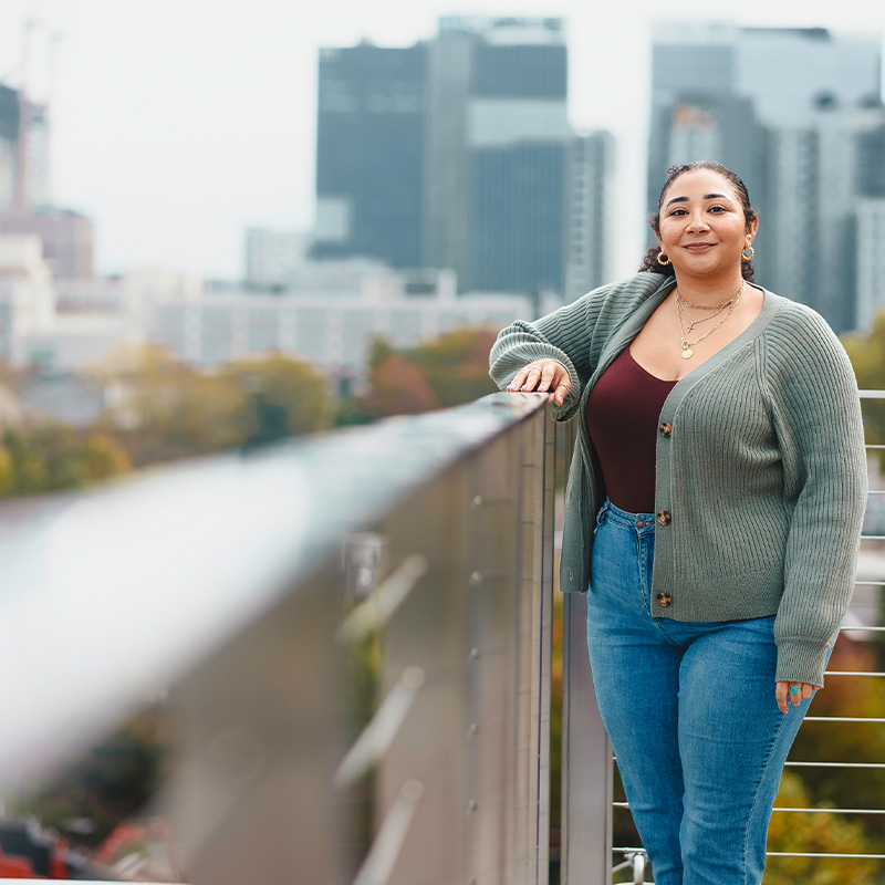 A Georgia Tech Scheller College of Business student stands with Midtown Atlanta buildings in the background.  