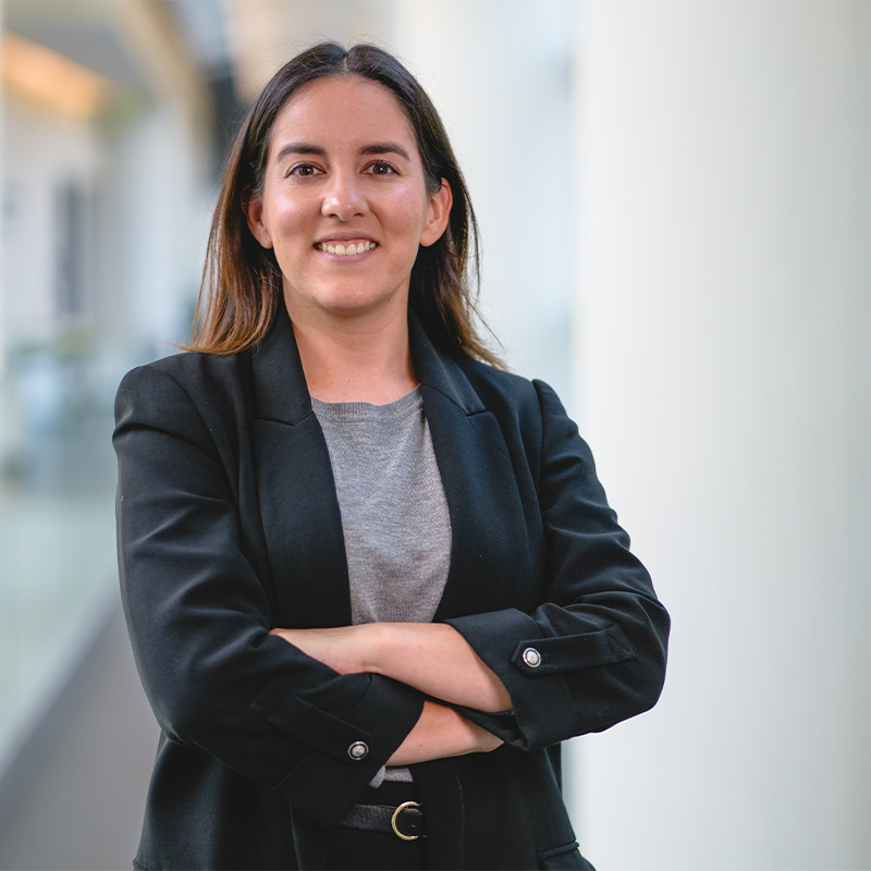 A woman dressed in professional suit jacket stands smiling 