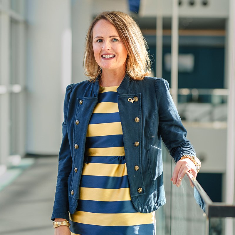 A woman in a gold and blue striped dress smiles