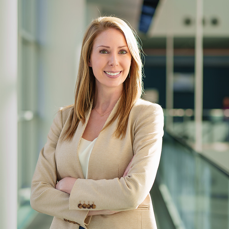 A woman stands with her arms folded, smiling