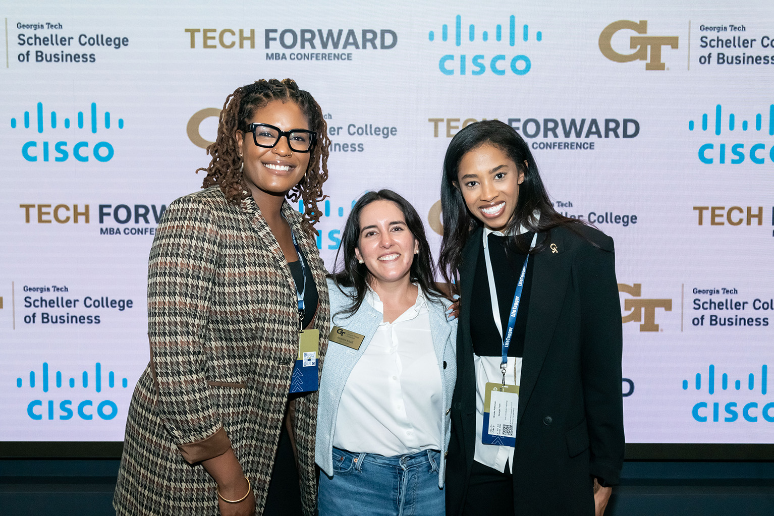 Three women stand with their arms on each other's shoulders