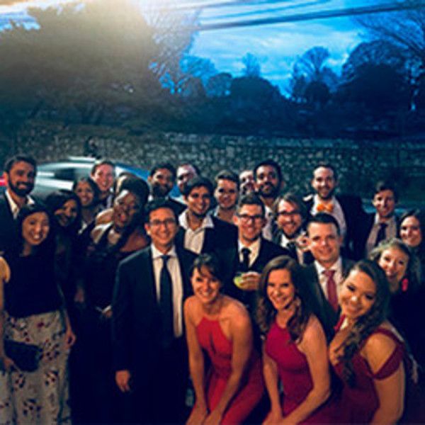 Women and men gather, dressed in formal attire for an MBA Prom event