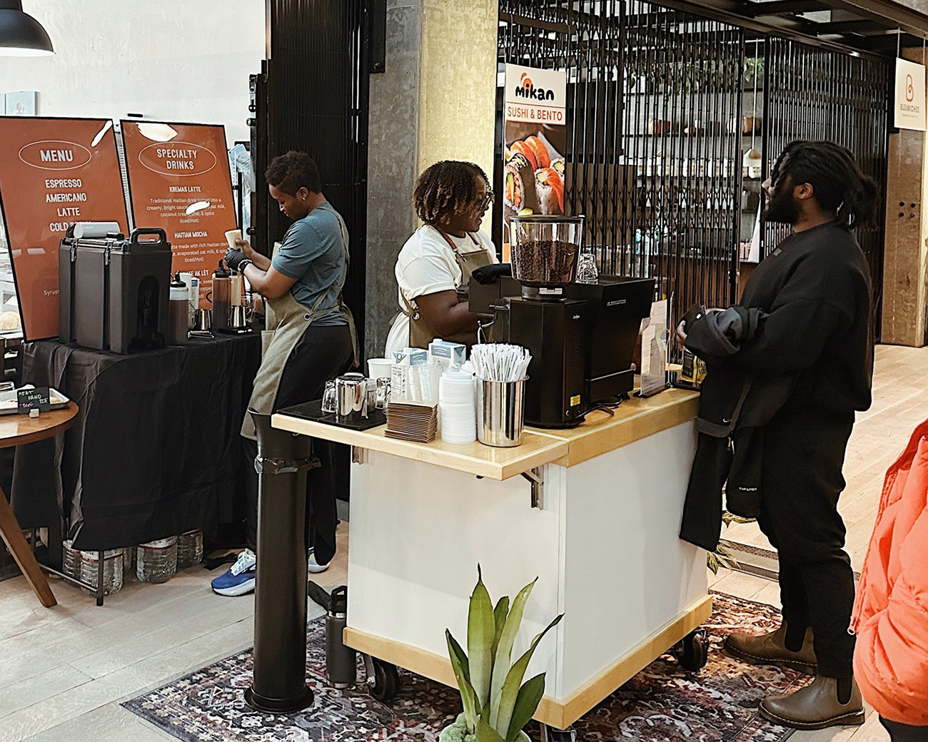 Two women work behind the counter of a coffee bar