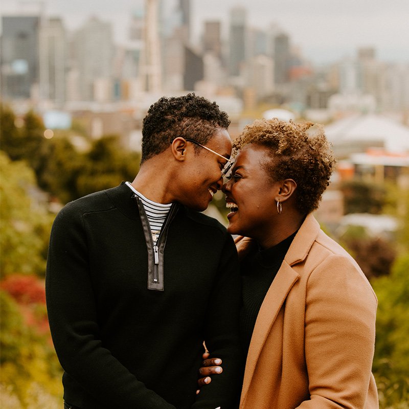 Two women hold hands outside in a park