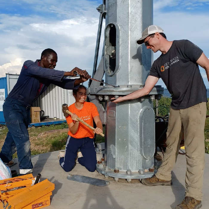 Amanda Ehrenhalt, with a hammer in hand, joins Renewvia employees in performing maintenance to a wind turbine